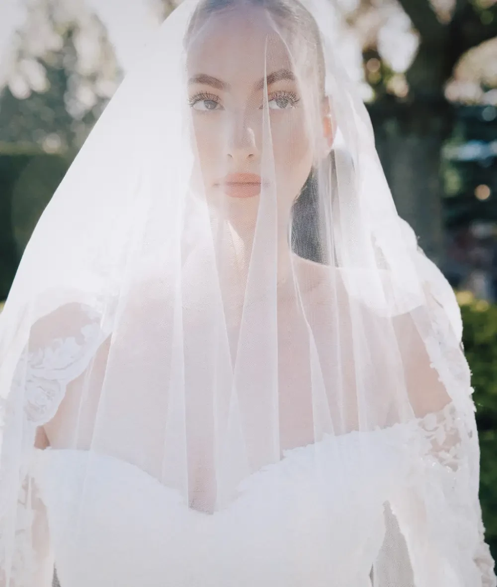Model wearing Bridal dress leaning next to a car